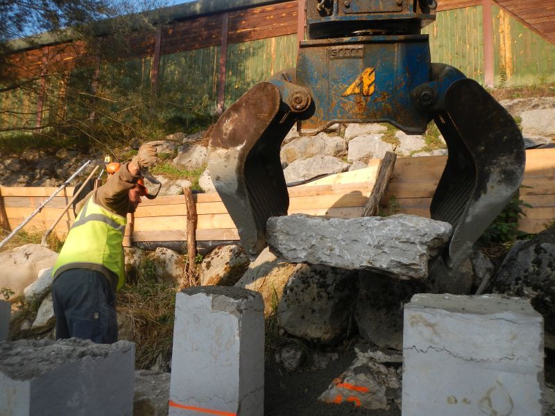 Bras de pelleteuse qui pose un bloc dans la rivière Lange