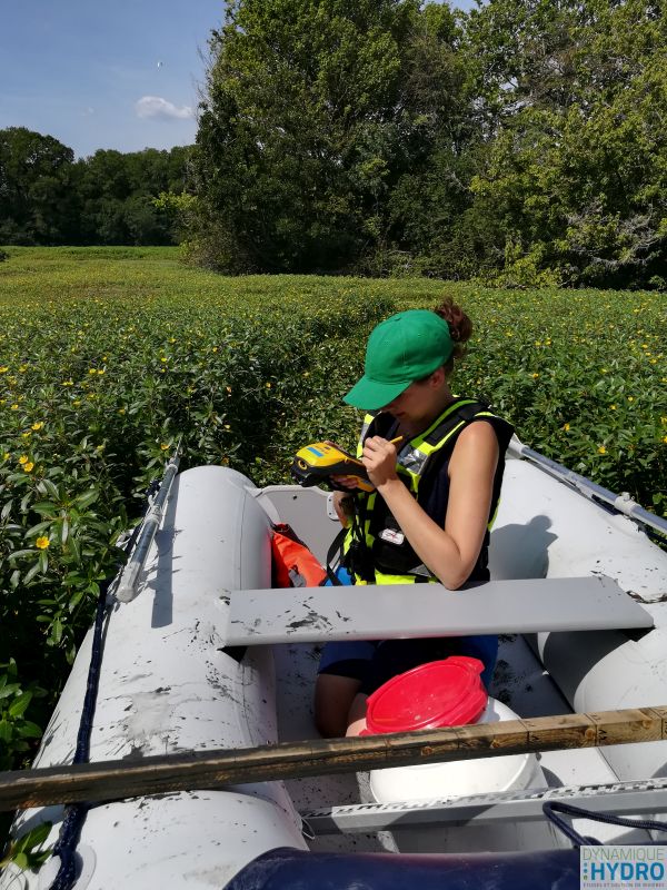 Alexia prend des points GPS (bathymétrie) dans un des lacs des zones humides des îles du Rhône dans la Drôme. Elle est assise dans notre bateau pneumatique Yam 275Sti