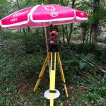 Le tachéomètre sous un parasol pour le protéger de la pluie