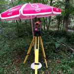 Le tachéomètre sous un parasol pour le protéger de la pluie